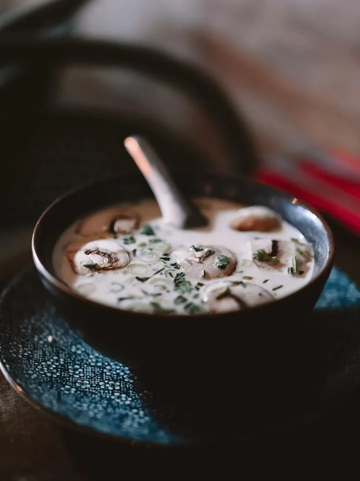 Soupe au lait de coco et aux champignons, dans un bol noir.