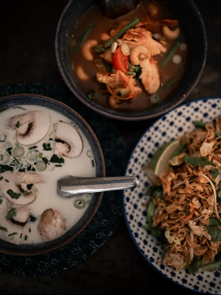 Vue du dessus : une soupe au lait de coco, un plat sauté et des nouilles sautées.