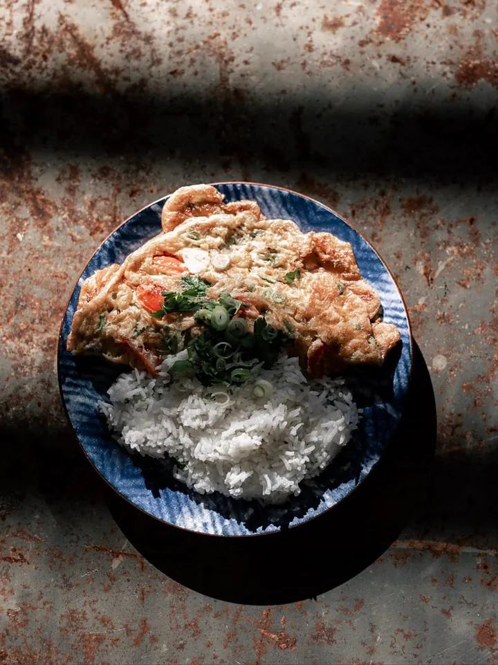 Un plat servi avec du riz blanc, dans une assiette bleue, vu du dessus.