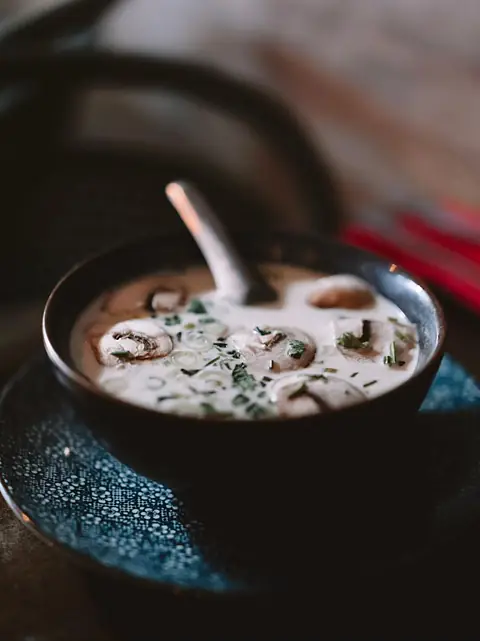 Soupe au lait de coco et aux champignons, dans un bol noir.